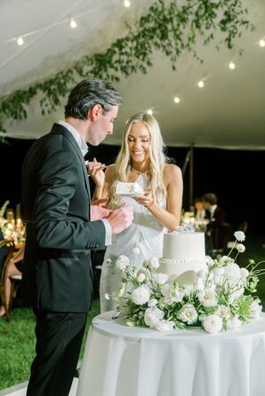 Groom in Classic Tuxedo and Bride With Down Hairstyle Cutting, Feeding White Wedding Cake