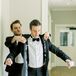 Groom is Helped into His Classic Black Tuxedo Jacket With Foliage-Print Liner