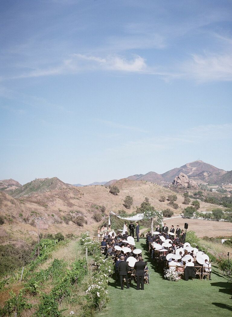 Outdoor wedding ceremony with parasols for guests