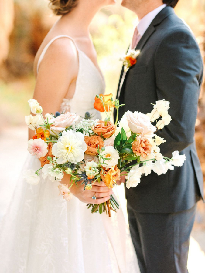 Couple holding white-and-orange wedding bouquet