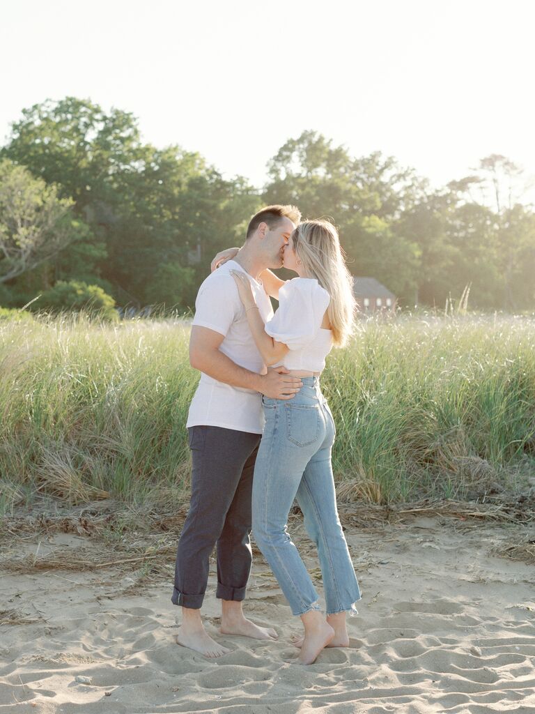 Couple kisses on the beach wearing casual clothes. 