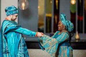 Bride and Groom in Traditional, Blue-and-Gold Yoruba Nigerian Wedding Attire Dancing