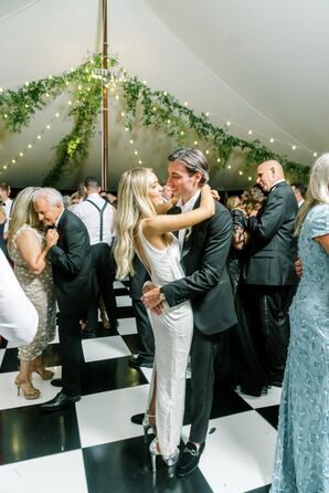 Bride in Foot Down, Low Back and Groom in Classic Tuxedo Dance Amongst Guests on Checkered Dance Floor