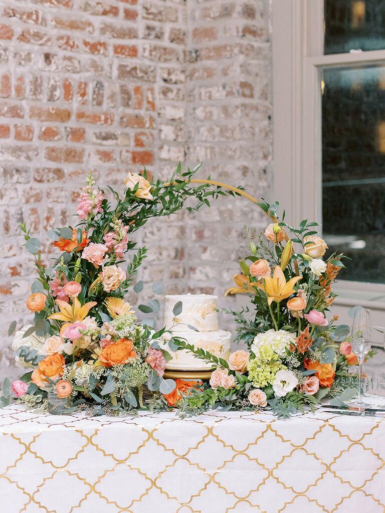 wedding cake display surrounded by a colorful floral hoop
