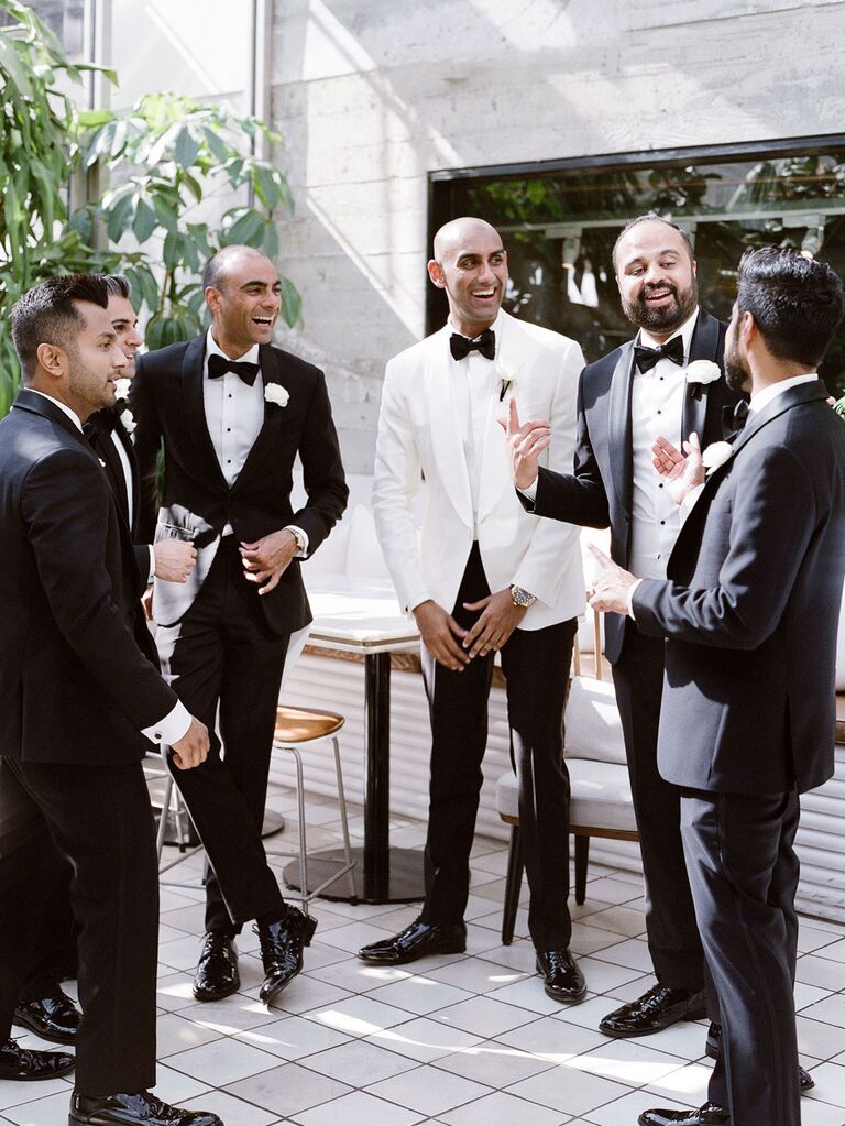 Candid photo of groom talking with groomsmen during wedding