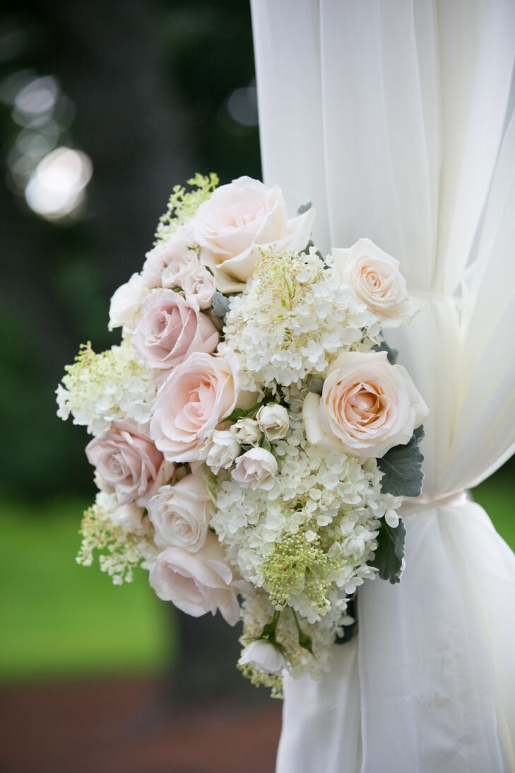 Blush and ivory-colored roses and hydrangeas were used to create two flower arrangements that flanked both sides of the couple's fabric-draped chuppah.
