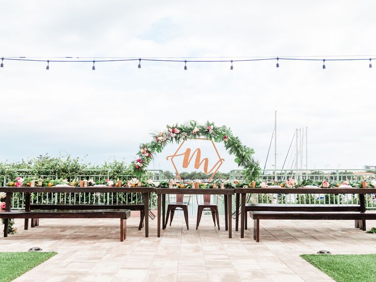 Reception with flower arch, custom sign and string lights