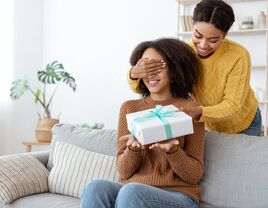 Woman surprising girlfriend with birthday present