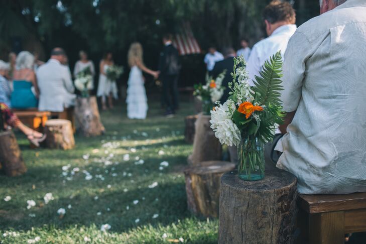 The couple placed tree stumps at the end of each aisle, topping them off with mason jars filled with white dahlias, orange poppies and ferns.