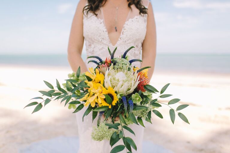 Bride holding sunflower bouquet on beach