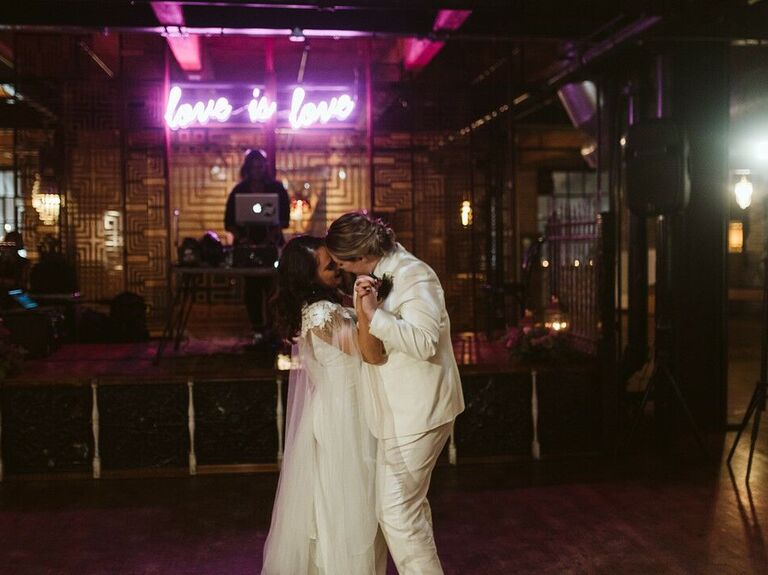 Couple slow dancing in front of neon sign