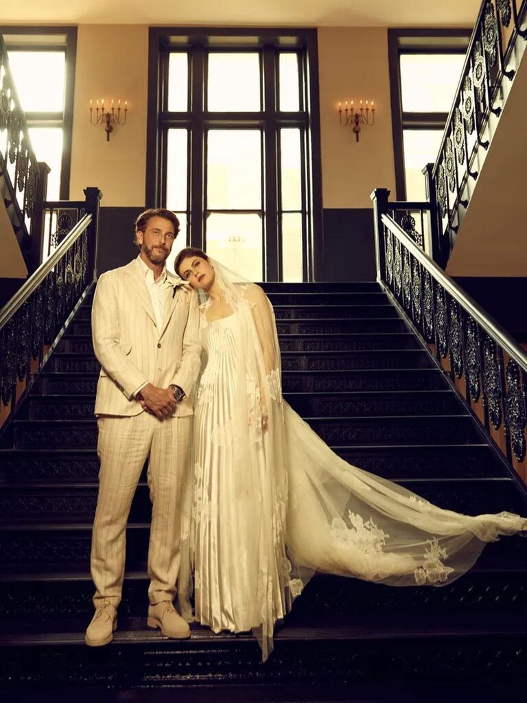 The newlyweds stand on a grand staircase. 