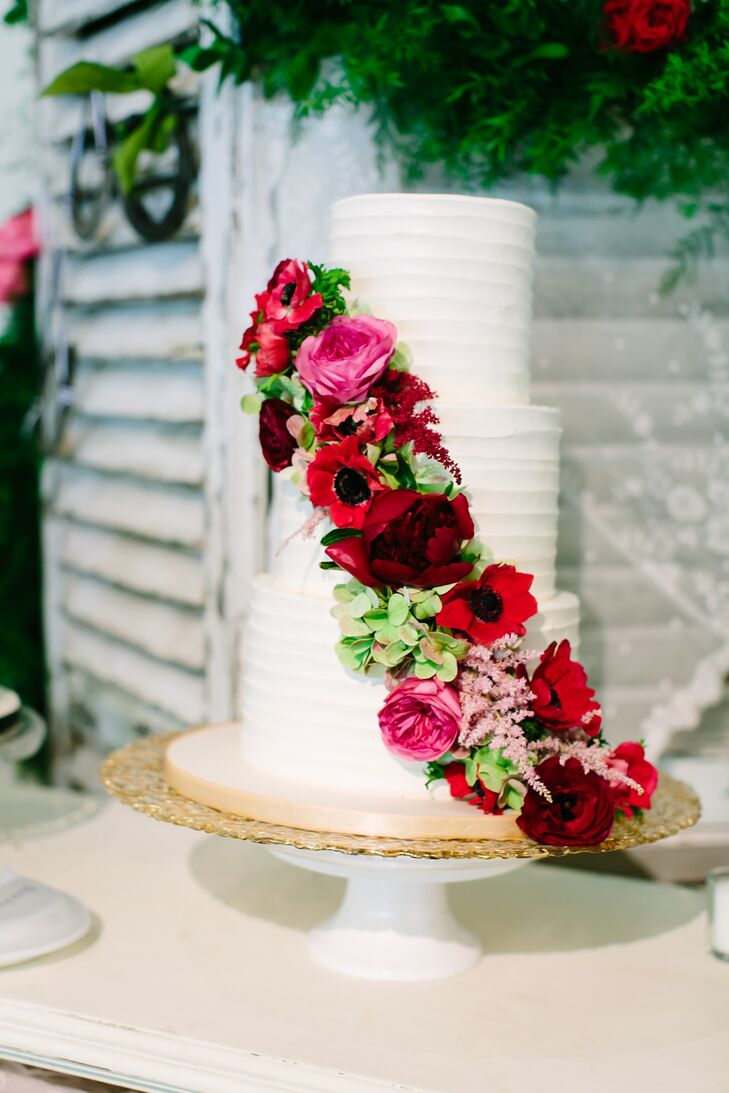 Simon Lee Bakery created this beautiful three-tier cake frosted in white buttercream. A cascade of roses, anemones, astilbes, garden roses and antique hydrangeas added a pop of color to the display.