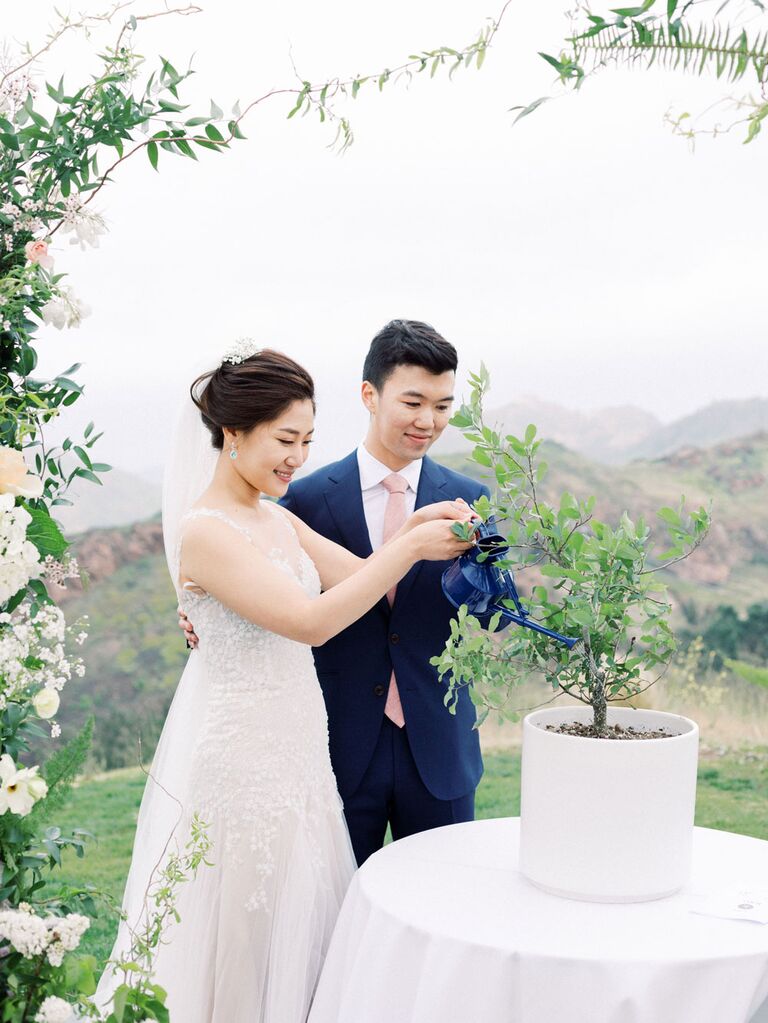 Bride and groom watering tree during tree-planing wedding unity ceremony