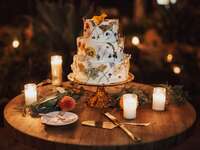 three tier buttercream wedding cake decorated with dried and pressed flowers in different colors