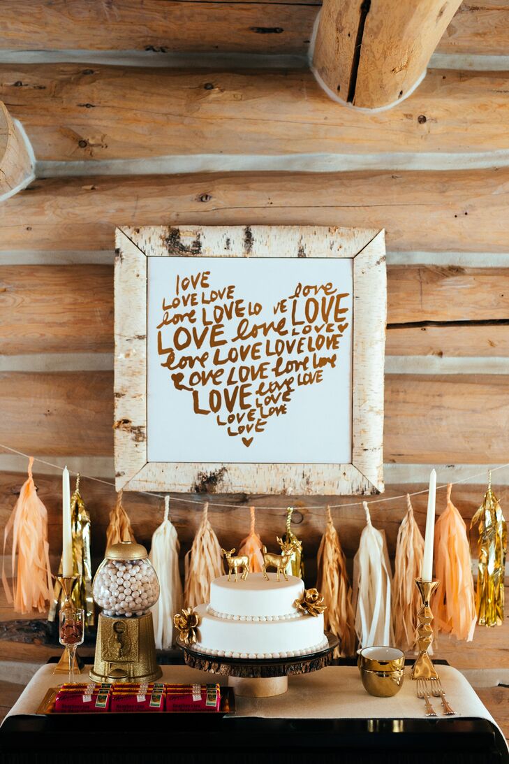 Suzi’s father handmade a Michigan birch tree picture frame to put around a white and gold canvas print that repeated the word “love” in the shape of a heart. The decoration hung over the cake table along with peach and gold tassels for a whimsical look that we can’t help but love.
