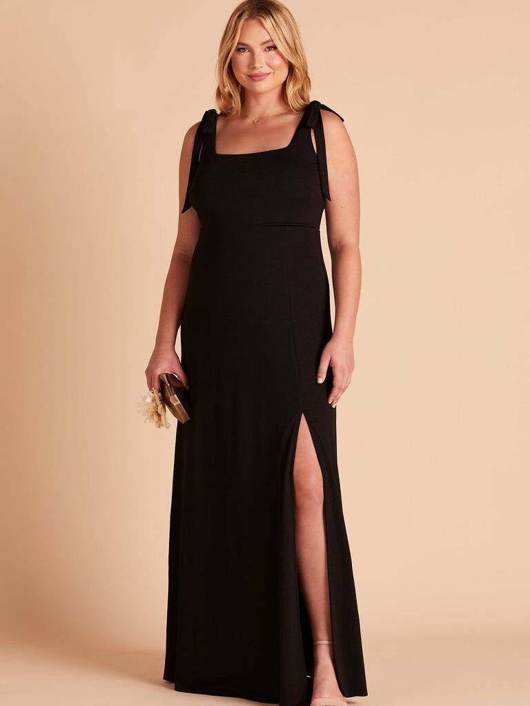 Model wears a floor-length black gown with tied straps. 