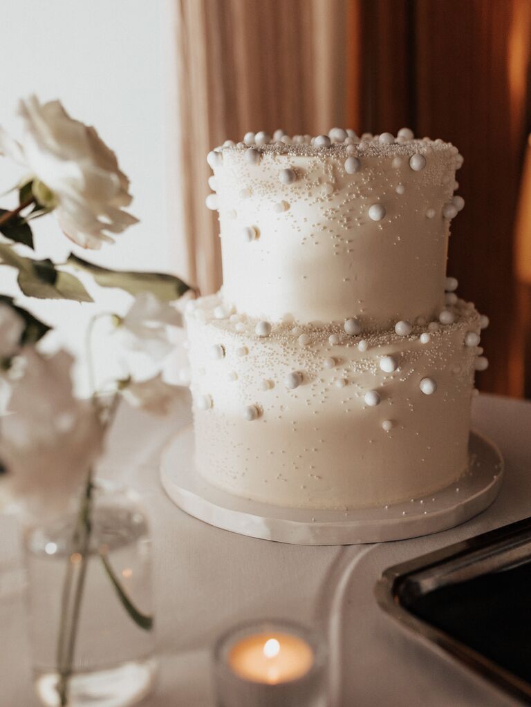 white two tier wedding cake decorated with sugar pearls and white sprinkles