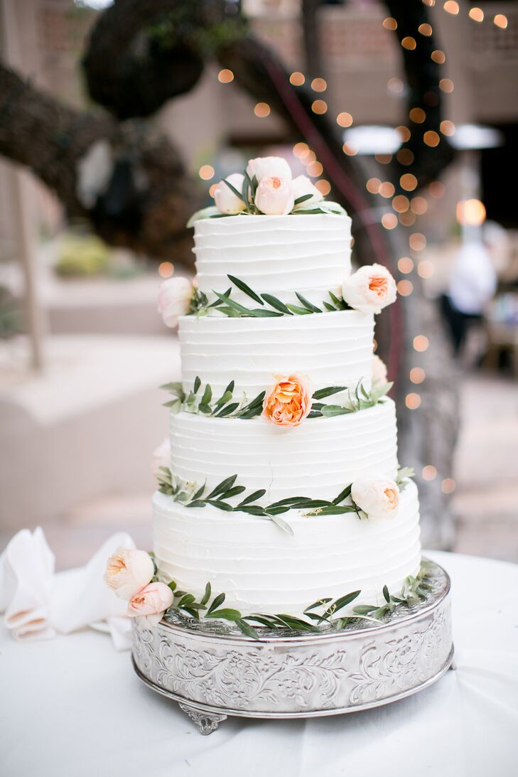 The couple's four-tier wedding cake was prepared by their venue, Boulders Resort & Spa in Carefree, Arizona. It featured blush and light orange florals and greenery. The white cake with a berry and custard filling sat atop a floral printed stand.