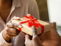 Couple exchanging 10th wedding anniversary gift with polka dot wrapping paper and red bow