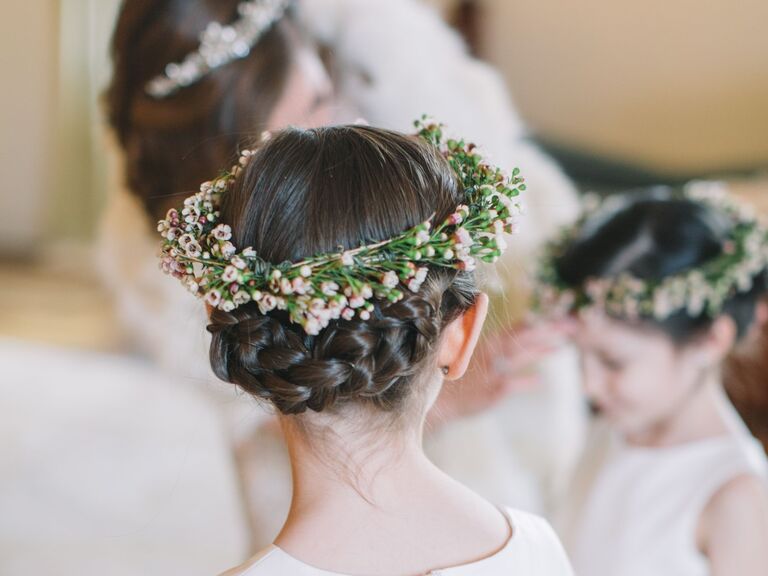 Flower girl wears her hair in a braided updo with a flower crown. 