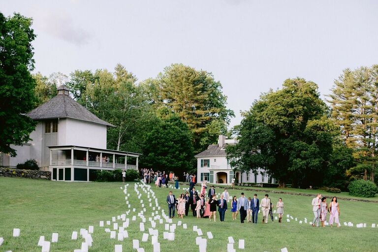 Wedding guests walking outside along luminaria-lined pathways