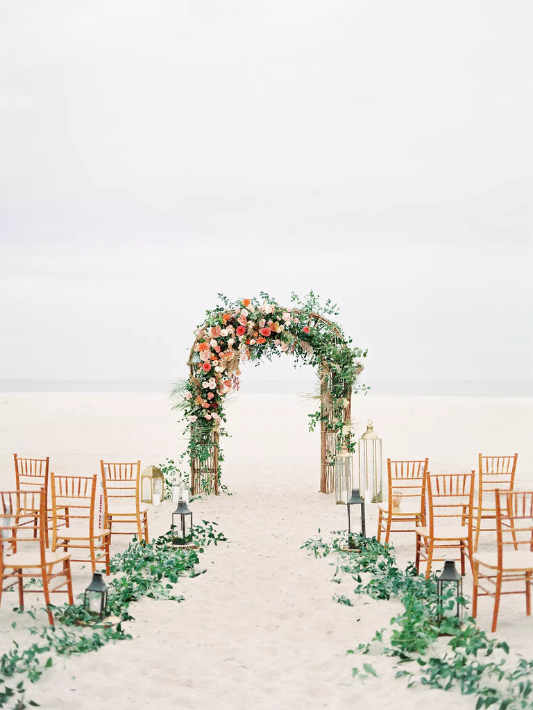 An asymmetrical wedding arch nestled among the beachside dunes.