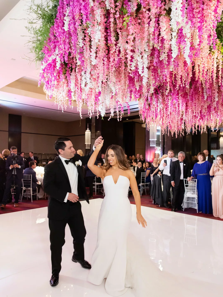 A couple dance beneath a stunning floral chandelier.