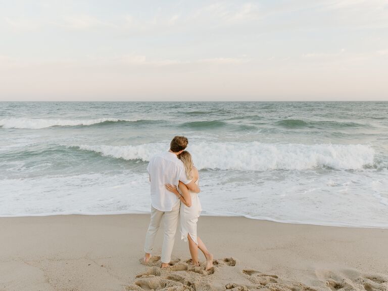Couple gazes out to sea at sunset. 