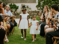 Flower girls wearing white holding hands walking down the aisle