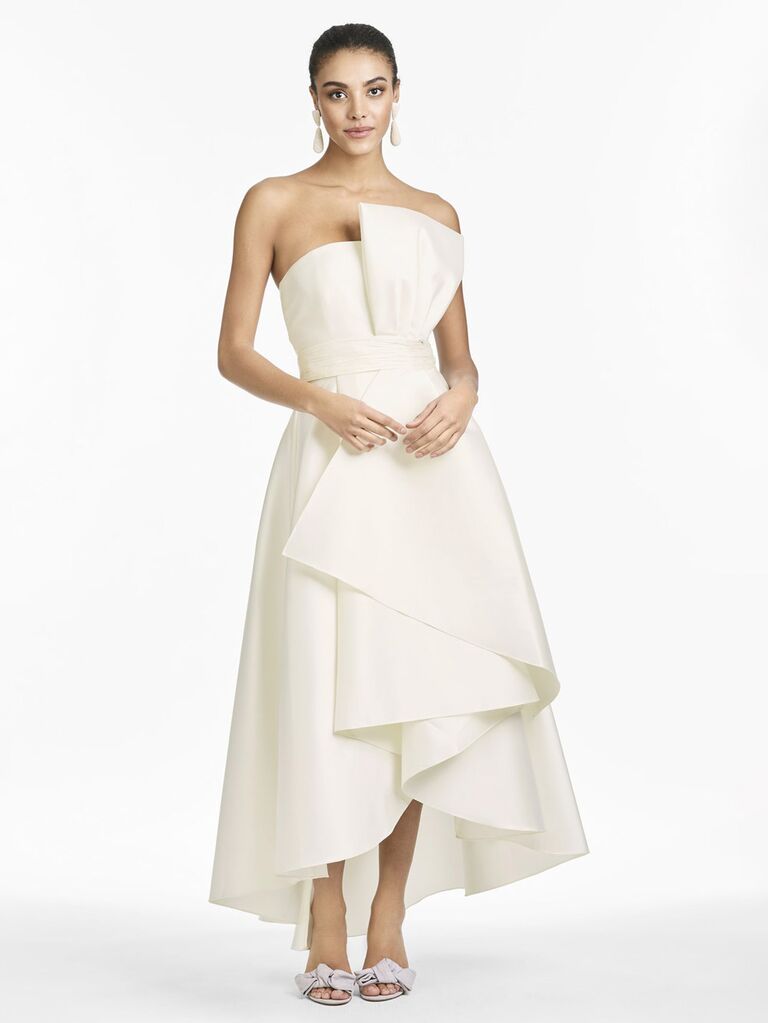sachin and babi white tea length strapless wedding dress with oversized bow front and lightly pleated high low skirt