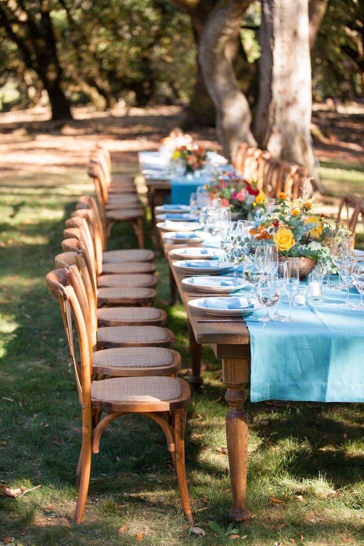 Bright teal table runners covered long wooden banquet tables at the outdoor reception and were topped with bright yellow and red blossoms—all keeping with the day's fire color spectrum.