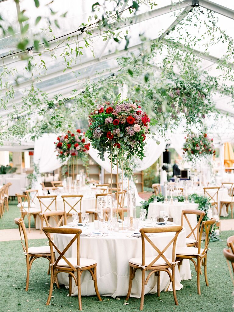 tented wedding reception with tall red rose and greenery centerpiece decorating round table