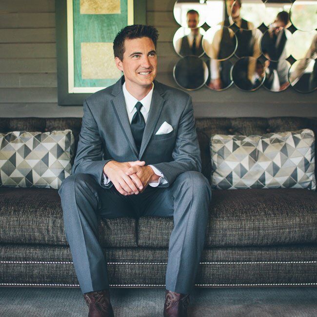 Brent wore a classic grey suit with a black tie and white pocket square. The groom tied in the day's theme to the outfit by sporting a pair of cowboy boots.
