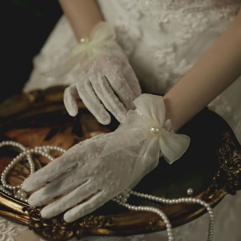 White gloves with a subtle leopard pattern with bows and imitation pearls at the wrist from Etsy