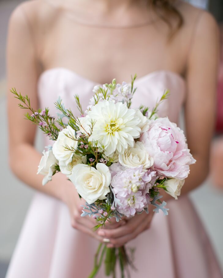 Each bridesmaid paired her classic look with a soft, romantic bouquet from Victoria's Garden. Blush peonies, white roses, white dahlias, pink delphiniums, dusty miller and greenery were gathered in a bold, glitter-covered gold ribbon for the arrangement.