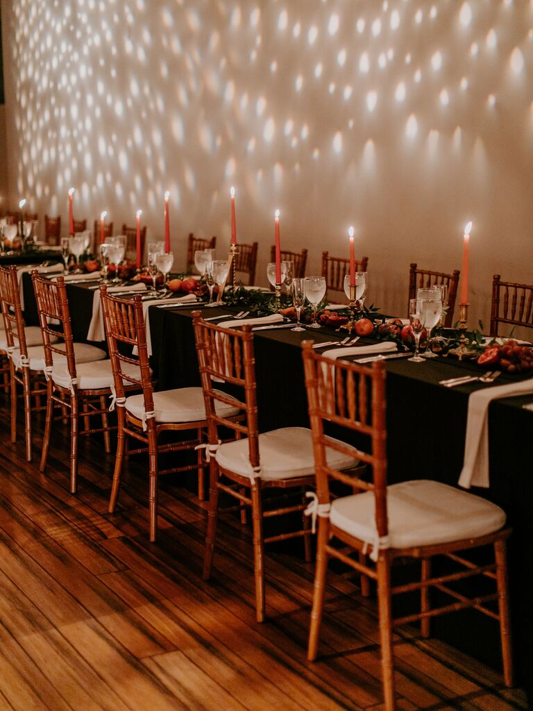 long wedding table with orange taper candles and sliced pomegranates