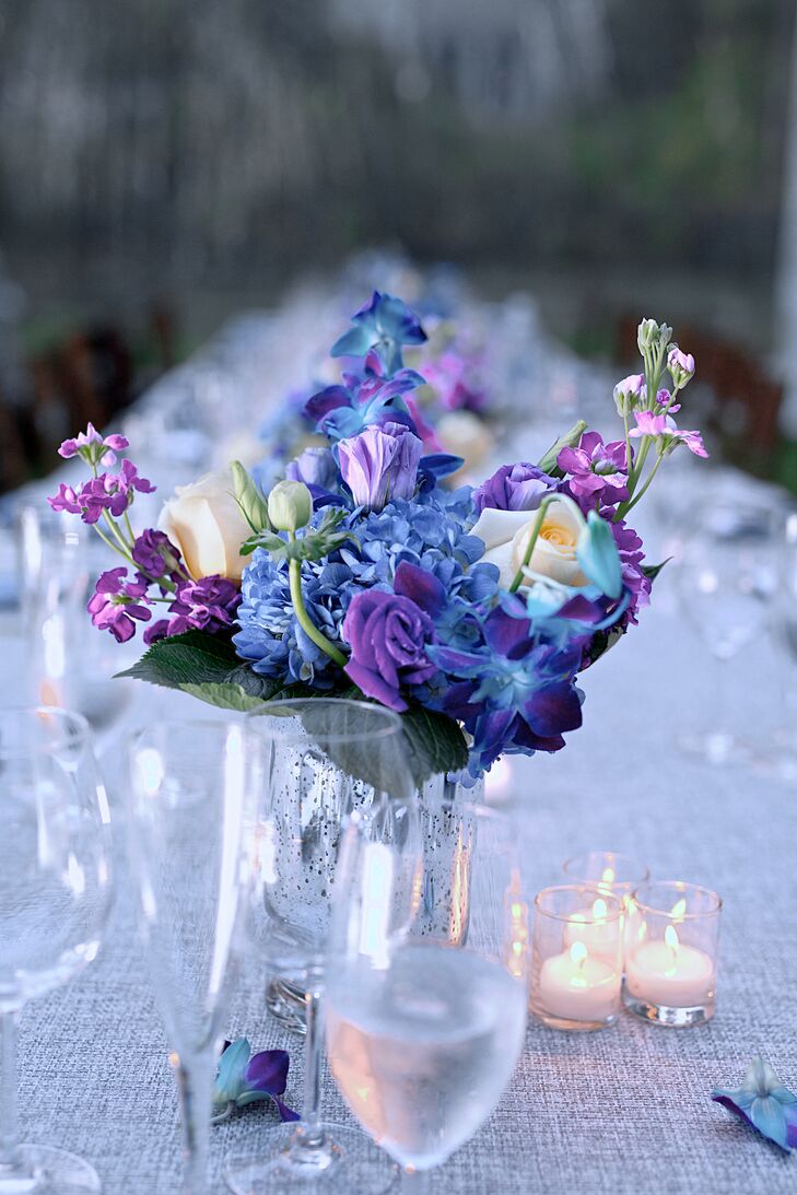 A mix of blue and purple flowers in low mercury glass vases topped the long reception tables.