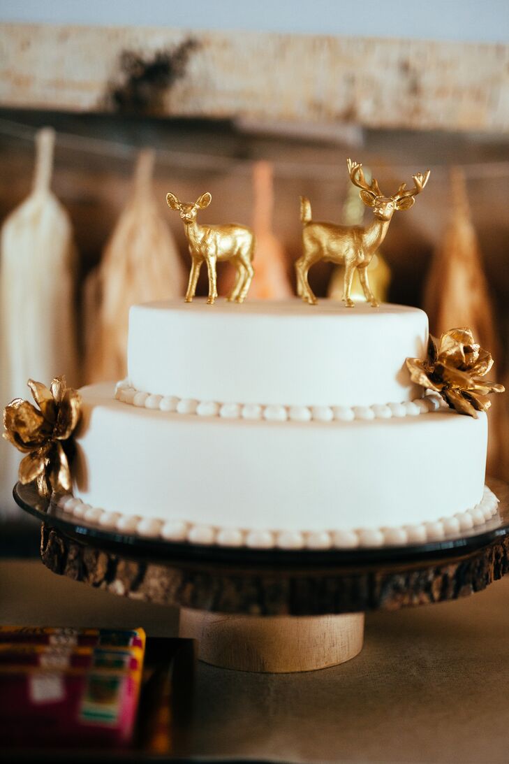 Suzi’s mother decorated the simple two-tier white wedding cake with gold spray-painted artificial flowers. She completed the look with a gold buck and doe on top.
