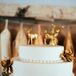 Suzi’s mother decorated the simple two-tier white wedding cake with gold spray-painted artificial flowers. She completed the look with a gold buck and doe on top.