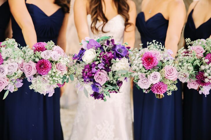 Incorporating the colors of the day—lavender and navy—each bouquet featured deep purple, lavender and white orchids and roses for Anne and lighter shades of purple and pink florals for the bridesmaids. All arrangements featured romantic touches of greenery.