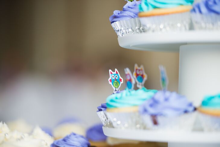 Tiny cartoon owl cupcake picks were placed in the delicious purple and blue frosted cupcake desserts.