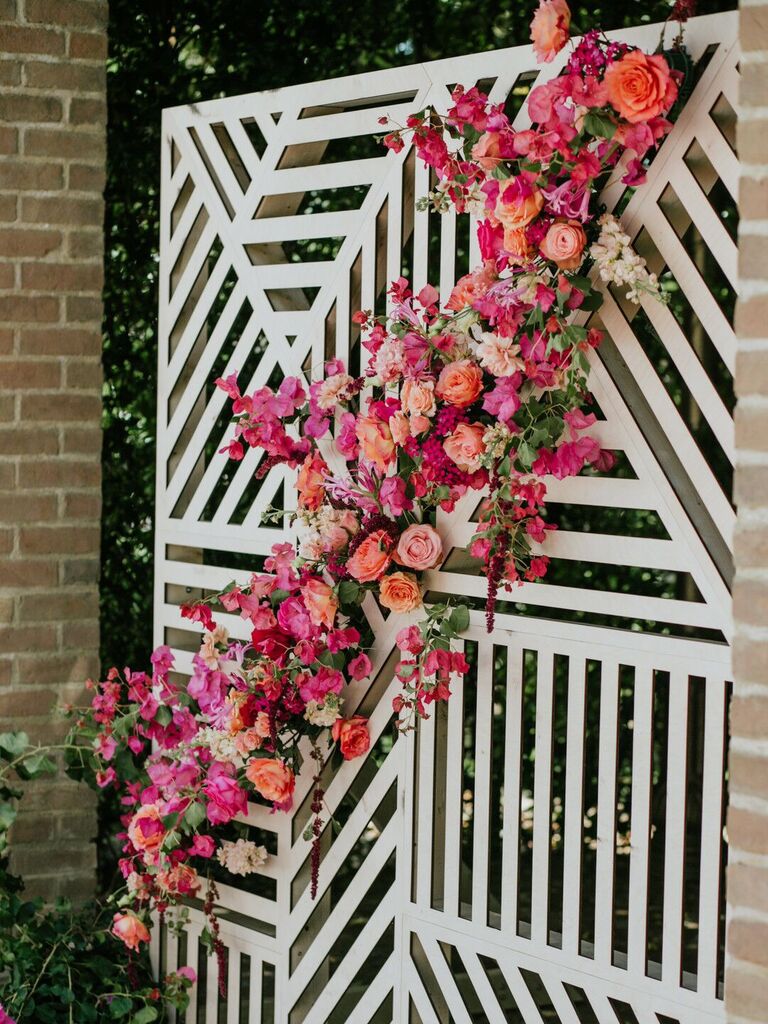 geometric wedding backdrop with pink, orange and red flowers diagonally across front
