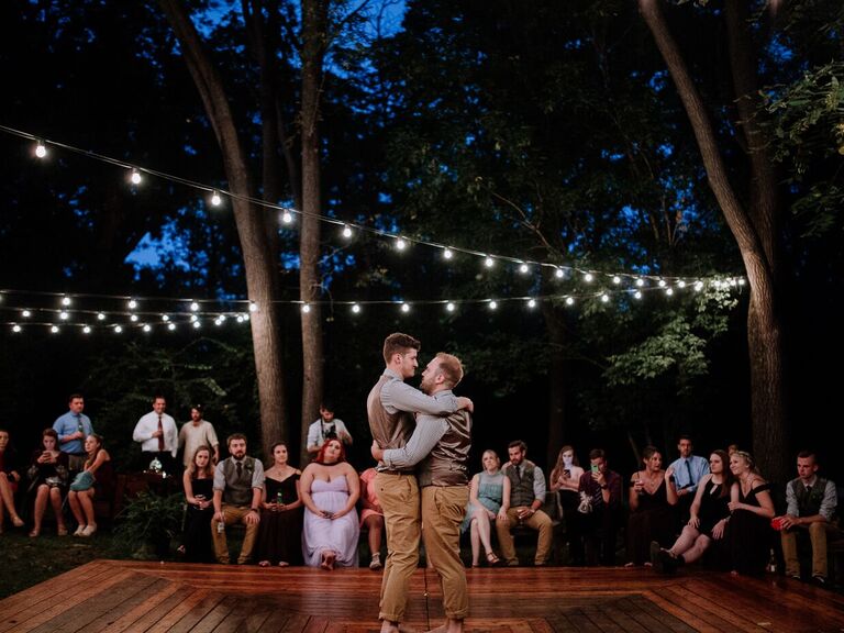 Couple dances on a wooden outdoor dance floor. 