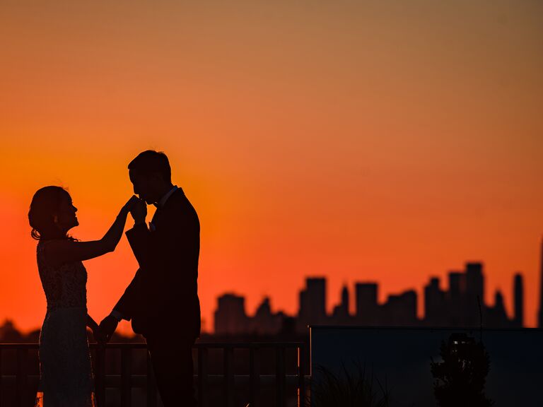 Groom kissing bride's hand silhouette