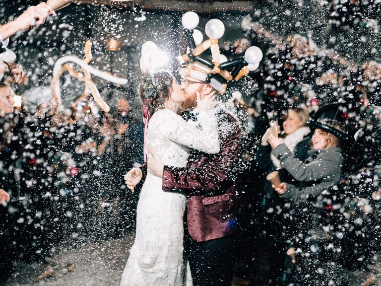 A couple kiss during a glitter and confetti wedding reception exit toss. 