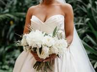 bride in strapless wedding dress holding all-white wedding bouquet