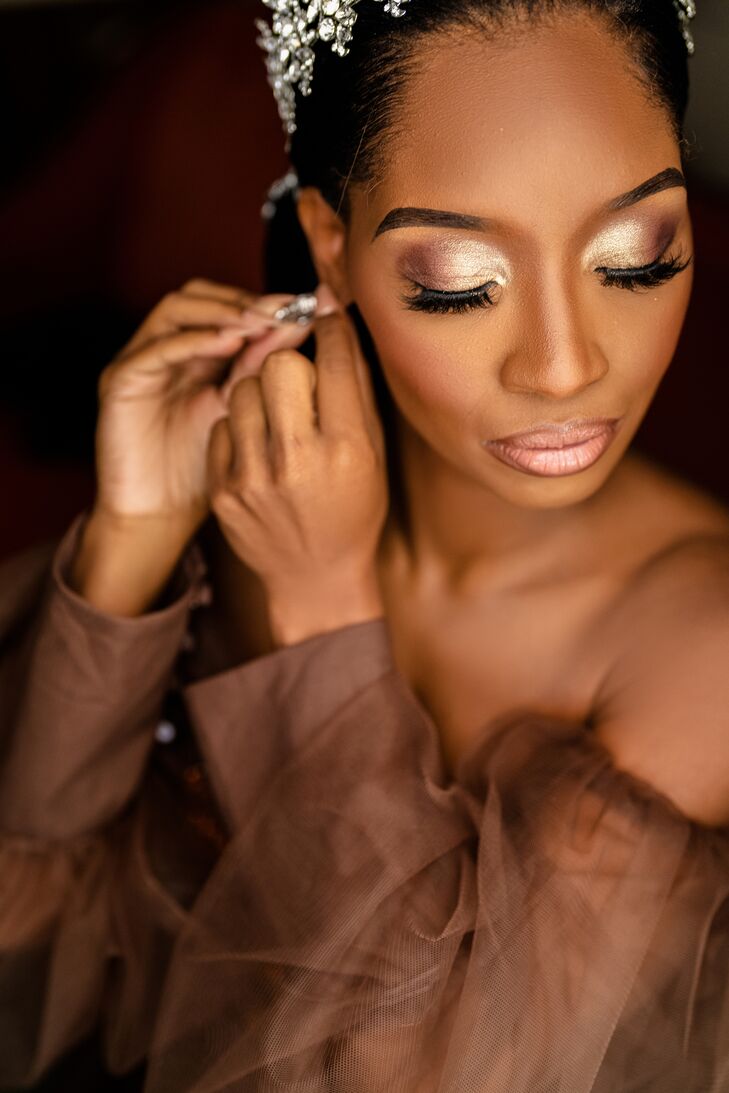 Bride in Gold Makeup Getting Ready and Putting on Earrings