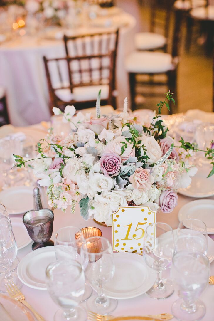 Dining tables covered in white linens had white table numbers decorated with gold polka dots, guiding guests to their seats! Lush arrangements of pastel-colored blooms accented the middle of the table for all to admire.