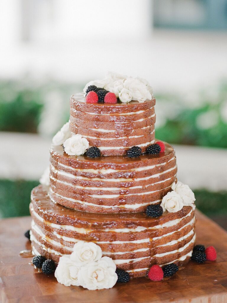 three tier naked wedding cake with sugar drip glaze icing, white roses and fresh blackberries and raspberries
